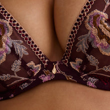 Load image into Gallery viewer, Close-up of a sheer lace bra with floral embroidery in purple, gold, and green on a dark burgundy mesh, worn by a model.