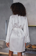Load image into Gallery viewer, The Ivory Deia robe is knee length made in beautiful heavy-weight pure silk satin. It is belted at the waist with a side pocket.
Tone on tone Calais lace appliqué on the shoulder and sleeves gives additional femininity to the stunning robe. Essential for those who love quality and refined, timeless style.