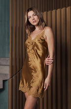 Load image into Gallery viewer, Woman wearing a gold lace nightgown against a wooden paneled wall.