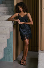 Load image into Gallery viewer, Woman in a black lace dress standing on a staircase.