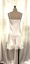 Load image into Gallery viewer, Made in Florence, this is a beautiful pure silk satin slip or nightgown. There is stunning deep appliqué lace on the bust. A side wide lace split leads from the thigh to the hem, continuing all around the base of the garment. There are French seams throughout for softness. The fine spaghetti straps are adjustable for the perfect fit. This nightslip is cut on the bias and panelled, giving a lovely flare and movement. May be worn as underwear, nightwear or outerwear. Ivory.