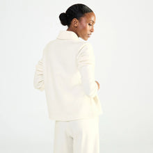Load image into Gallery viewer, A model shown from the back wearing a cream-colored structured bed jacket and matching trousers against a plain white studio background.