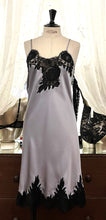 Load image into Gallery viewer, Silver/Black. Made in Italy, this is a beautiful long pure silk satin night/slip. There is stunning deep appliqué lace at the bust and hem. There are French seams throughout for softness. The fine spaghetti straps are adjustable for the perfect fit. This nightslip is cut on the bias and panelled giving lovely flare and movement. Perfect for bed or daywear. May be worn as underwear, nightwear or outerwear. Composition: 100% Silk Satin Italian Lace 100% polyamide Machine washable Length 82cm from nape.