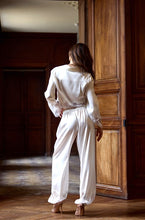 Load image into Gallery viewer, Wonderfully playful Harem style silk satin pyjamas. The button front Crop Top has a revere collar, the jacket hem has a wide appliqué lace detail, mirrored in the deep appliqué lace on the cuffs. The trousers has an elastic waist band at the back, and flat to the front. The bottom of the pants has a wide appliqué lace band, tapering into a cuff at the ankle. French seams throughout. Perfect for sleep or leisure wear.
Fabric: 50% Silk, 38% Viscose, 12% Spandex
Lace: 100% Polyester.