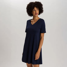 Load image into Gallery viewer, A woman wearing a navy short sleeve cotton silk above knee length 90 cm long nightdress. It has a silk trim on the V-neck as well as on the sleeves and the hem.
