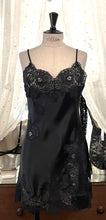 Load image into Gallery viewer, Made in Florence, Italy, this is a beautiful short pure silk satin night/slip. There is stunning deep appliqué lace on the bust and front of the garment. A side split leads to the hem, all with the same rich lace detail. There are French seams throughout for softness. The fine spaghetti straps are adjustable for the perfect fit. This nightslip is cut on the bias and panelled, giving lovely flare and movement. Perfect for bed or daywear. May be worn as underwear, nightwear or outerwear. Black/Black.