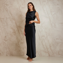 Load image into Gallery viewer, Woman wearing a black silk Slip skirt with matching top against a textured beige background