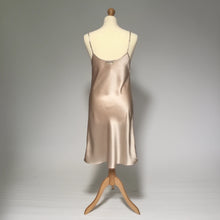 Load image into Gallery viewer, A silk satin slip dress in a champagne beige color, displayed on a mannequin against a neutral gray studio background.
