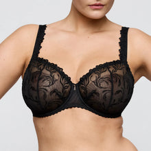 Load image into Gallery viewer, A close-up of a model wearing a black lace underwire bra with floral lace detailing and scalloped edges against a light gray background.