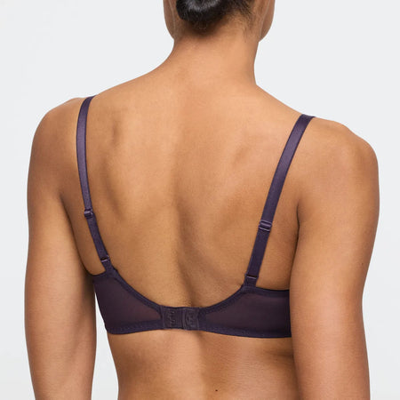Person wearing a dark purple bra on a light gray background