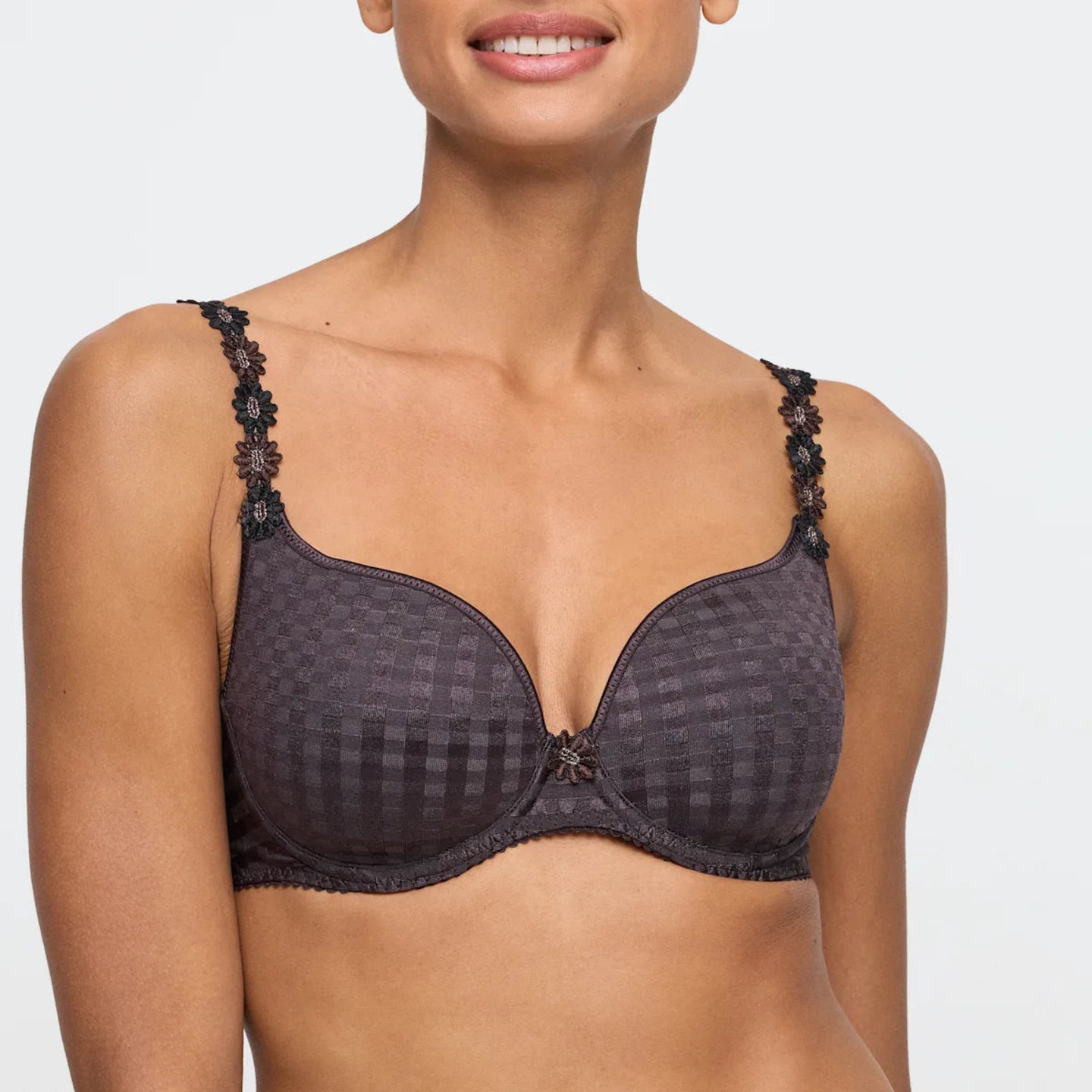 Woman wearing a dark patterned bra on a white background