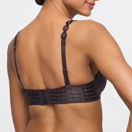 Black bra with floral details on straps worn by a model against a light gray background