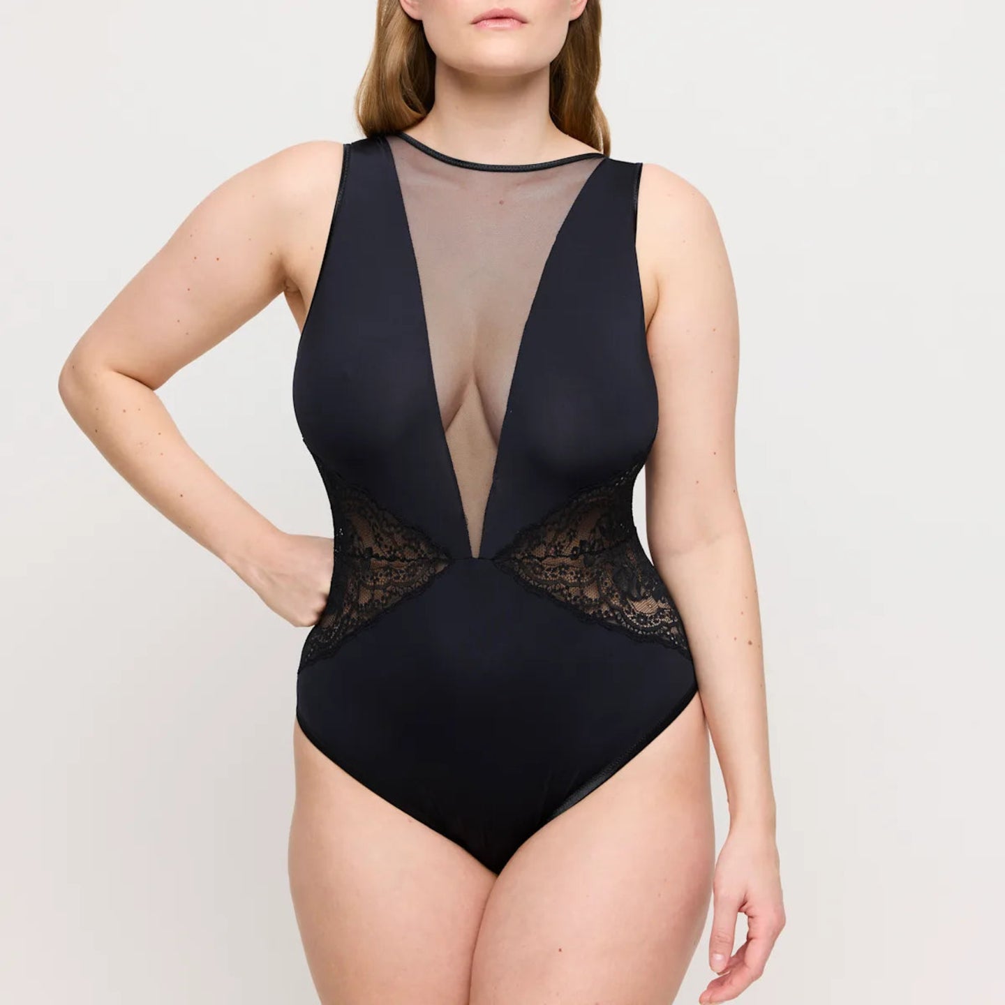 Black swimsuit with sheer mesh and lace details on a plain background