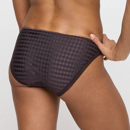 Person wearing a patterned black underwear on a plain background