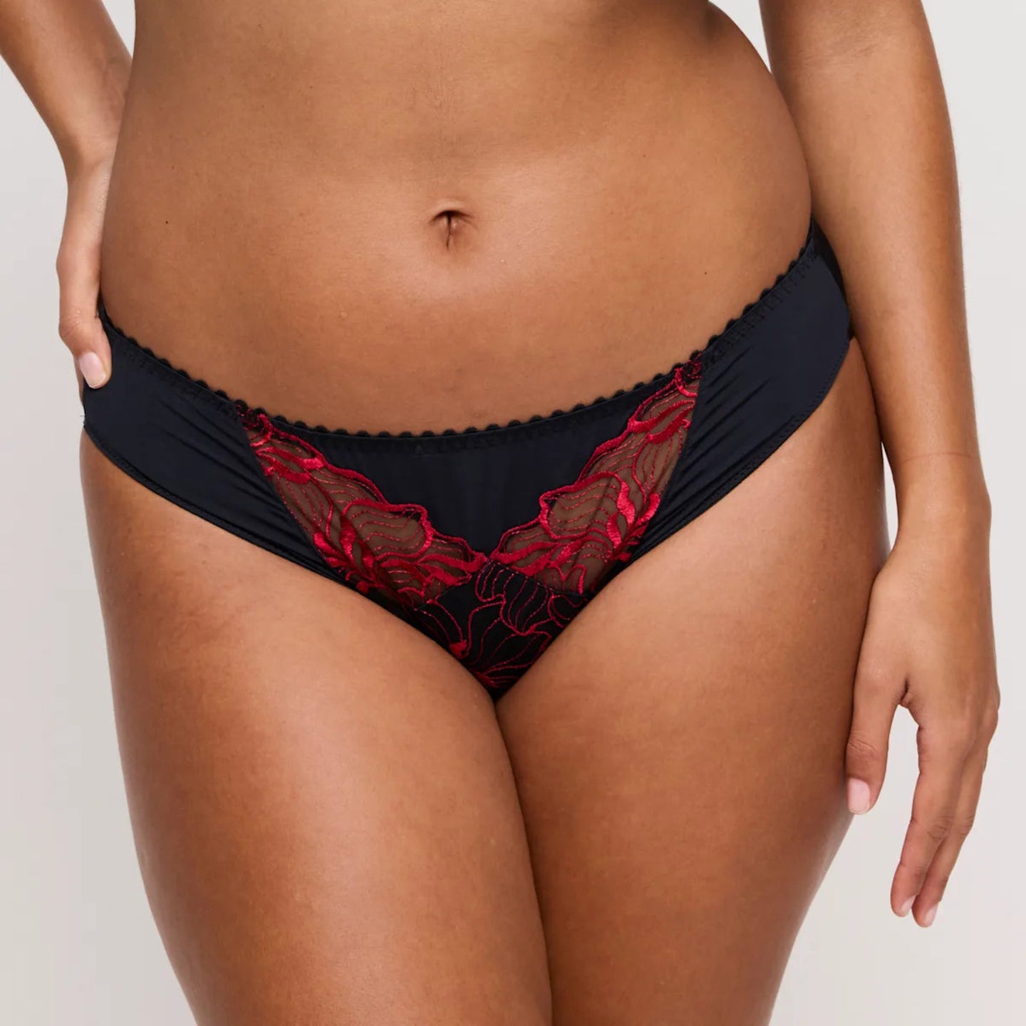 Black lace underwear with red trim on a neutral background