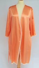 Load image into Gallery viewer, SALE Beautiful pure silk robe with a delicate vintage style lace trim completely surroundingthe entire garment. To just above the knee, this short robe is a wonder for travel or ever lounging around the home. The apricot colour suits all skin types, is feminine and not at all intrusive!   Fabric Content: 100% Pure Silk Made in Italy Machine washable.
