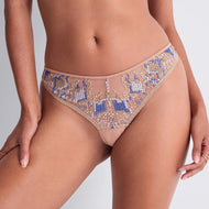 Close-up of a person wearing nude mesh panties with intricate blue and beige geometric French embroidery. The background is a soft gray, conveying elegance and style.