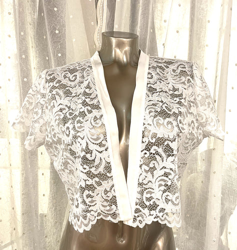 Made in Florence, this is a beautiful all lace cropped over bolero jacket. Soft satin trim on the on the neckline continuing down the front edges. Perfect as a bedjacket, as outerwear particularly good for bridal wear.  Composition: All Lace: 67% cotton, 33% polyamide. Machine washable.