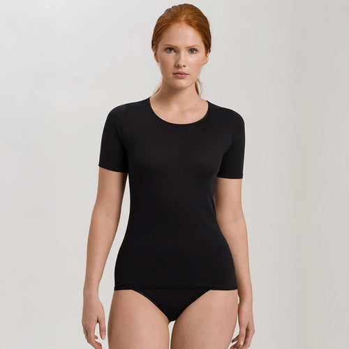 A woman wearing a black seamless cotton T-Shirt style top. It has a short sleeves and a round neck. The bottom of the shirt reaches the hips. 
