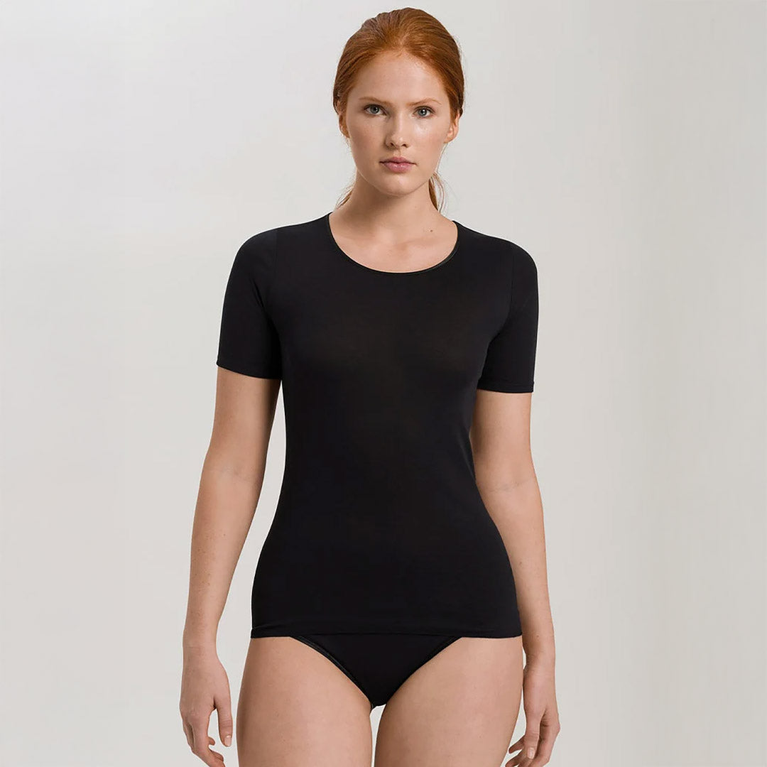 A woman wearing a black seamless cotton T-Shirt style top. It has a short sleeves and a round neck. The bottom of the shirt reaches the hips. 