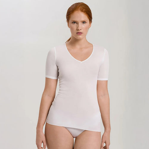 A woman wearing a white seamless cotton T-Shirt style top. It has a short sleeves and a V-Neck. The bottom of the shirt reaches the hips. 