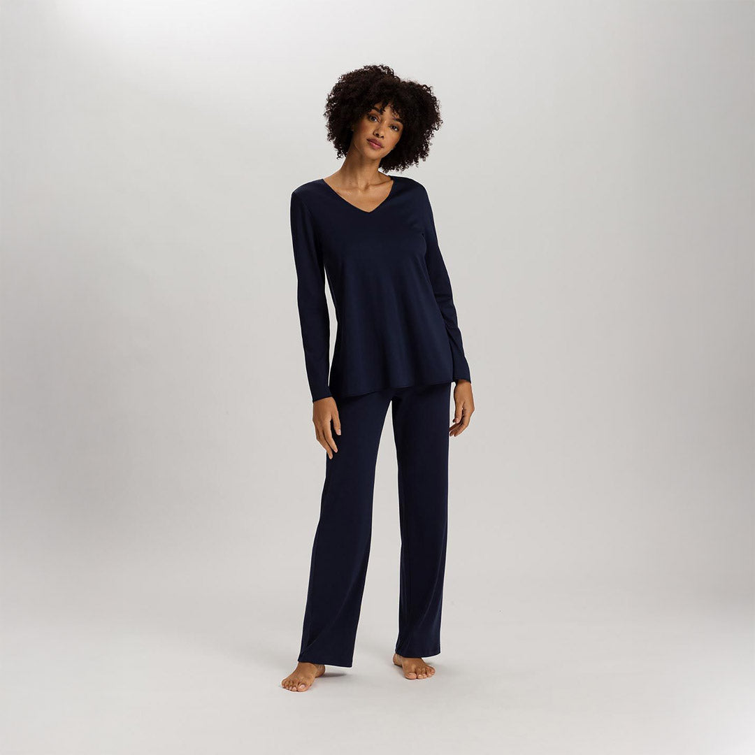 A woman wearing Deep Navy long sleeve pyjamas. It has a lovely V-neck with a delicate silk trim. This beautiful trim is also on the sleeves and the bottom of the top. The trousers are also full length with a straight leg for ultimate comfort.