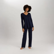A woman wearing Deep Navy long sleeve pyjamas. It has a lovely V-neck with a delicate silk trim. This beautiful trim is also on the sleeves and the bottom of the top. The trousers are also full length with a straight leg for ultimate comfort.
