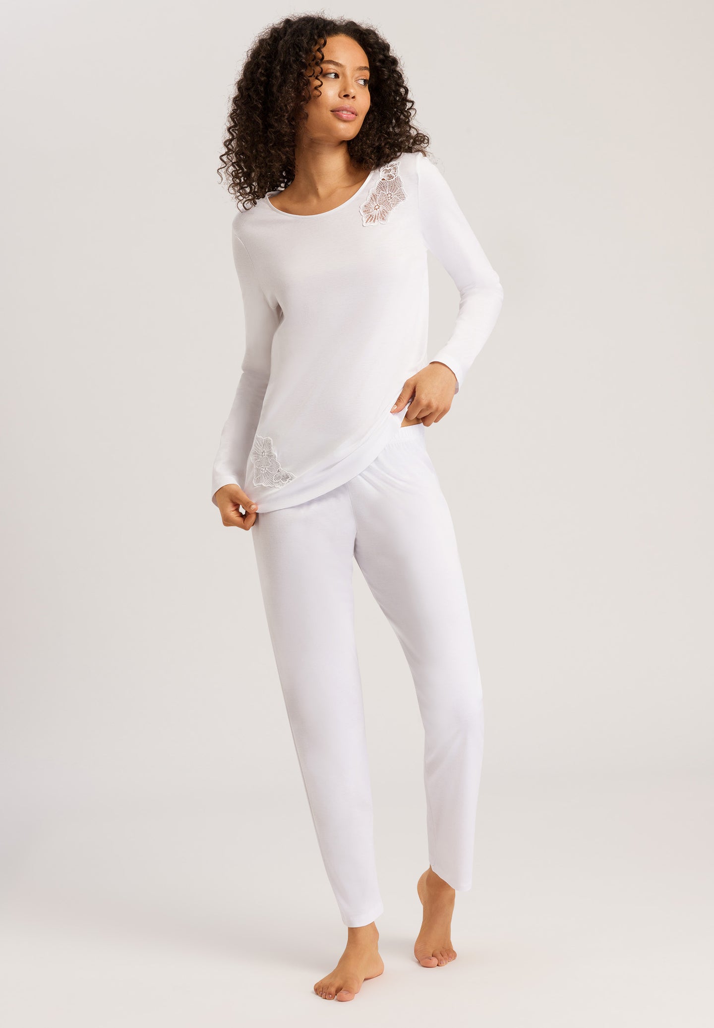 Made from 100% soft mercerised knitted cotton, Rounded neckline with an appliqué lace inset at the neck & front hem. Perfect item for lounging or sound sleep. Gentle rounded collar, long sleeves and with loose fitting trousers, elasticated at the waist.  Composition: 100% Pure Cotton 100% Polyester Lace  Made in Europe Machine washable. Pure White.