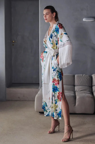 Beryl Full length robe. 
A fabulous floral pattern with an embroidered rendering. Entirely made of mixed silk satin, with a floral print on an ivory background, it seduces with its fluid and majestic look.
The pattern, both poetic and bright, evokes the refinement of watercolor embroidery, in a palette of deep and vibrant shades.
The cut is straight, loose, crossed at the front. The waist is accentuated by a matching belt with decorative long fringe. The wide sleeves, also enhanced with silky fringe.