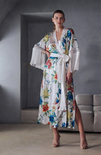 Load image into Gallery viewer, Beryl Full length robe. 
A fabulous floral pattern with an embroidered rendering. Entirely made of mixed silk satin, with a floral print on an ivory background, it seduces with its fluid and majestic look.
The pattern, both poetic and bright, evokes the refinement of watercolor embroidery, in a palette of deep and vibrant shades.
The cut is straight, loose, crossed at the front. The waist is accentuated by a matching belt with decorative long fringe. The wide sleeves, also enhanced with silky fringe.

