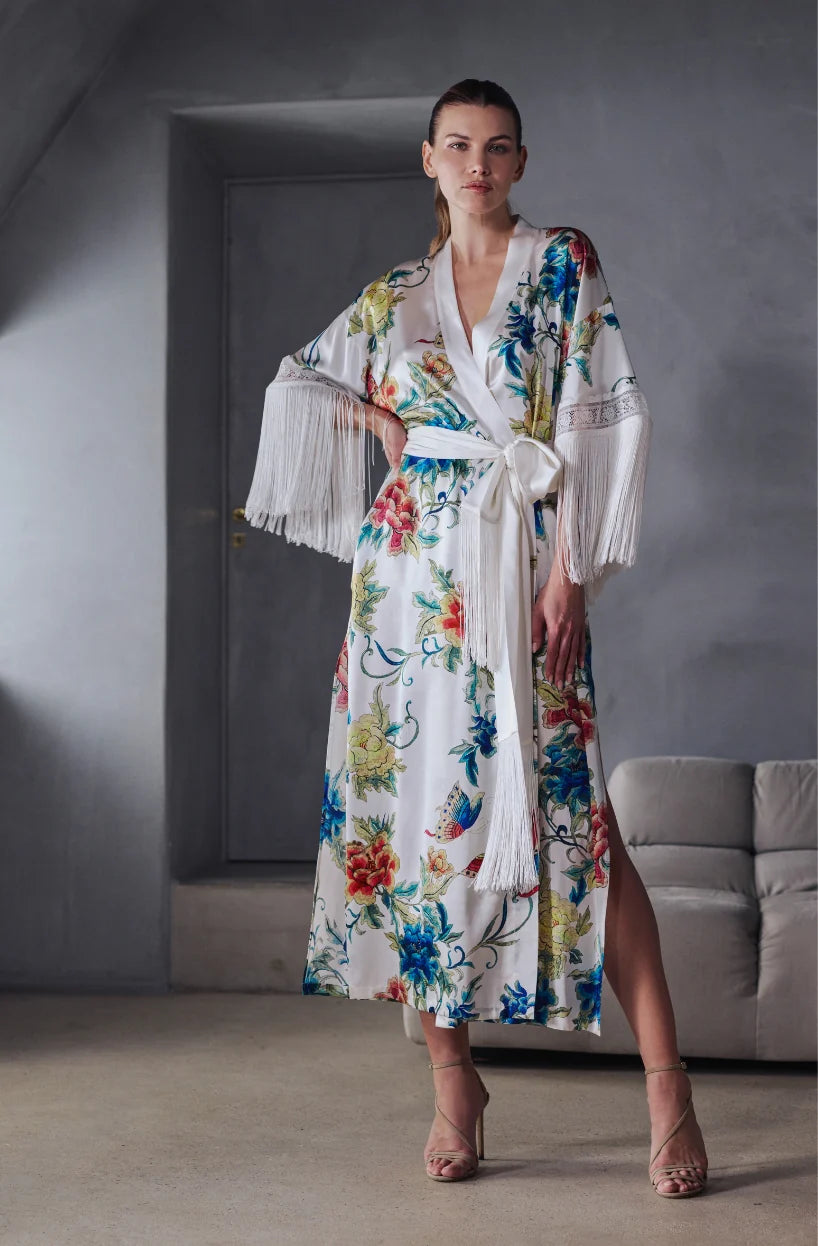 Beryl Full length robe. 
A fabulous floral pattern with an embroidered rendering. Entirely made of mixed silk satin, with a floral print on an ivory background, it seduces with its fluid and majestic look.
The pattern, both poetic and bright, evokes the refinement of watercolor embroidery, in a palette of deep and vibrant shades.
The cut is straight, loose, crossed at the front. The waist is accentuated by a matching belt with decorative long fringe. The wide sleeves, also enhanced with silky fringe.
