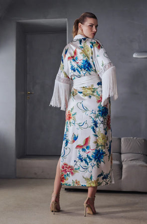 Beryl Full length robe. 
A fabulous floral pattern with an embroidered rendering. Entirely made of mixed silk satin, with a floral print on an ivory background, it seduces with its fluid and majestic look.
The pattern, both poetic and bright, evokes the refinement of watercolor embroidery, in a palette of deep and vibrant shades.
The cut is straight, loose, crossed at the front. The waist is accentuated by a matching belt with decorative long fringe. The wide sleeves, also enhanced with silky fringe.