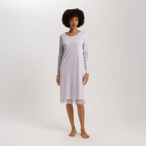 A woman wearing a Pink Lavender long sleeve 110cm length nightdress. It has a lovely round neckline and the hem has delicate embroidered lace trim on tulle.The garment has a lovely feminine flow to it.