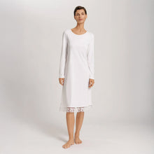 Load image into Gallery viewer, A woman wearing an Off White long sleeve 110cm length nightdress. It has a lovely round neckline and the hem has delicate embroidered lace trim on tulle. The garment has a lovely feminine flow to it.
