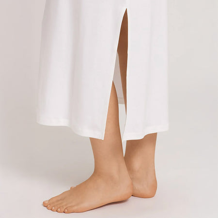 A close up of the hem of an Off White full length nightdress. Highlighting the featured slip on the side of the hem.