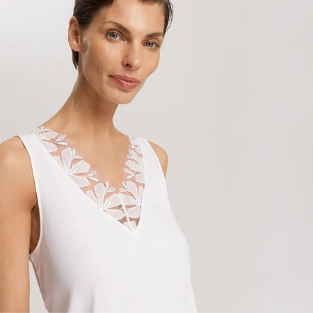 A close up of a woman wearing an Off White sleeveless nightdress. Highlighting a lace trim on the V-neckline.