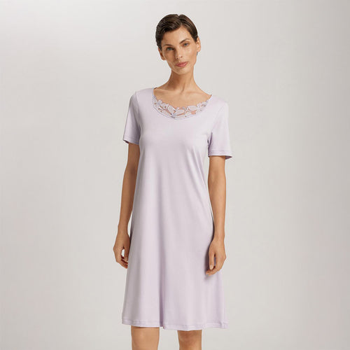 A woman wearing a Pink Lavender short (knee length) nightdress and short sleeves with a lace trim on the neckline. The garment has a lovely feminine flow to it.