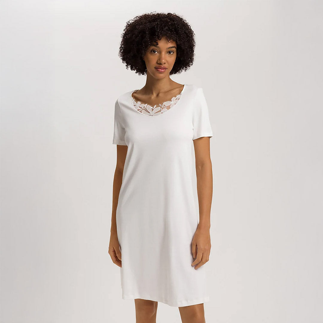 A woman wearing an Off White short (knee length) nightdress with short sleeves and a lace trim on the neckline. The garment has a lovely feminine flow to it.