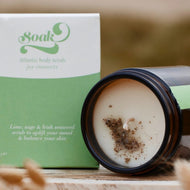Jar of candle with 'Soak' packaging on a wooden surface