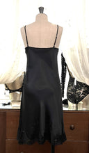 Load image into Gallery viewer, Black/Black. Made in Italy, this is a beautiful long pure silk satin night/slip. There is stunning deep appliqué lace at the bust and hem. There are French seams throughout for softness. The fine spaghetti straps are adjustable for the perfect fit. This nightslip is cut on the bias and panelled giving lovely flare and movement. Perfect for bed or daywear. May be worn as underwear, nightwear or outerwear.   Composition: 100% Silk Satin Italian Lace 100% polyamide Machine washable Length 82cm from nape.
