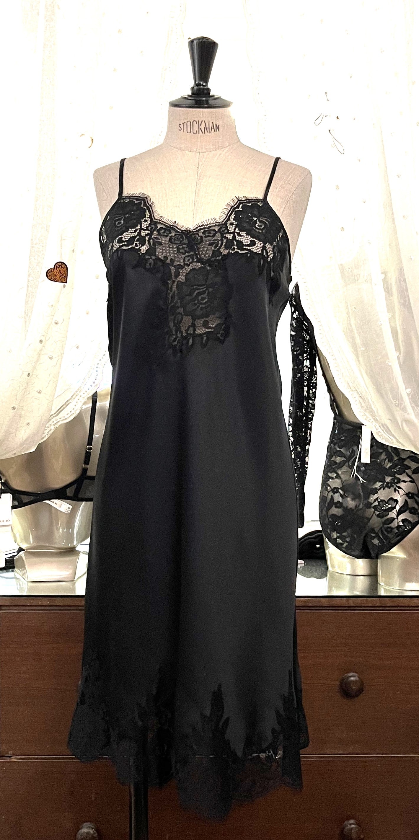 Black/Black. Made in Italy, this is a beautiful long pure silk satin night/slip. There is stunning deep appliqué lace at the bust and hem. There are French seams throughout for softness. The fine spaghetti straps are adjustable for the perfect fit. This nightslip is cut on the bias and panelled giving lovely flare and movement. Perfect for bed or daywear. May be worn as underwear, nightwear or outerwear.   Composition: 100% Silk Satin Italian Lace 100% polyamide Machine washable Length 82cm from nape.