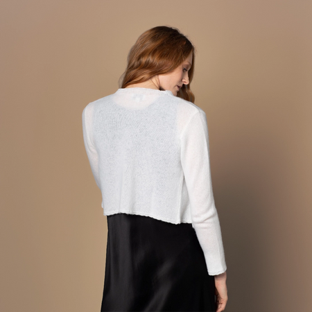 Woman wearing a Vinage Ivory cashmere bed jacket over a white shirt against a brown background - back image