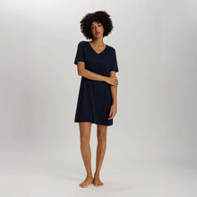 Load image into Gallery viewer, A woman wearing a navy short sleeve cotton silk above knee length 90 cm long nightdress. It has a silk trim on the V-neck as well as on the sleeves and the hem. 
