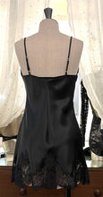 Load image into Gallery viewer, Made in Florence, Italy, this is a beautiful short pure silk satin night/slip. There is stunning deep appliqué lace on the bust and front of the garment. A side split leads to the hem, all with the same rich lace detail. There are French seams throughout for softness. The fine spaghetti straps are adjustable for the perfect fit. This nightslip is cut on the bias and panelled, giving lovely flare and movement. Perfect for bed or daywear. May be worn as underwear, nightwear or outerwear. Black/Black.
