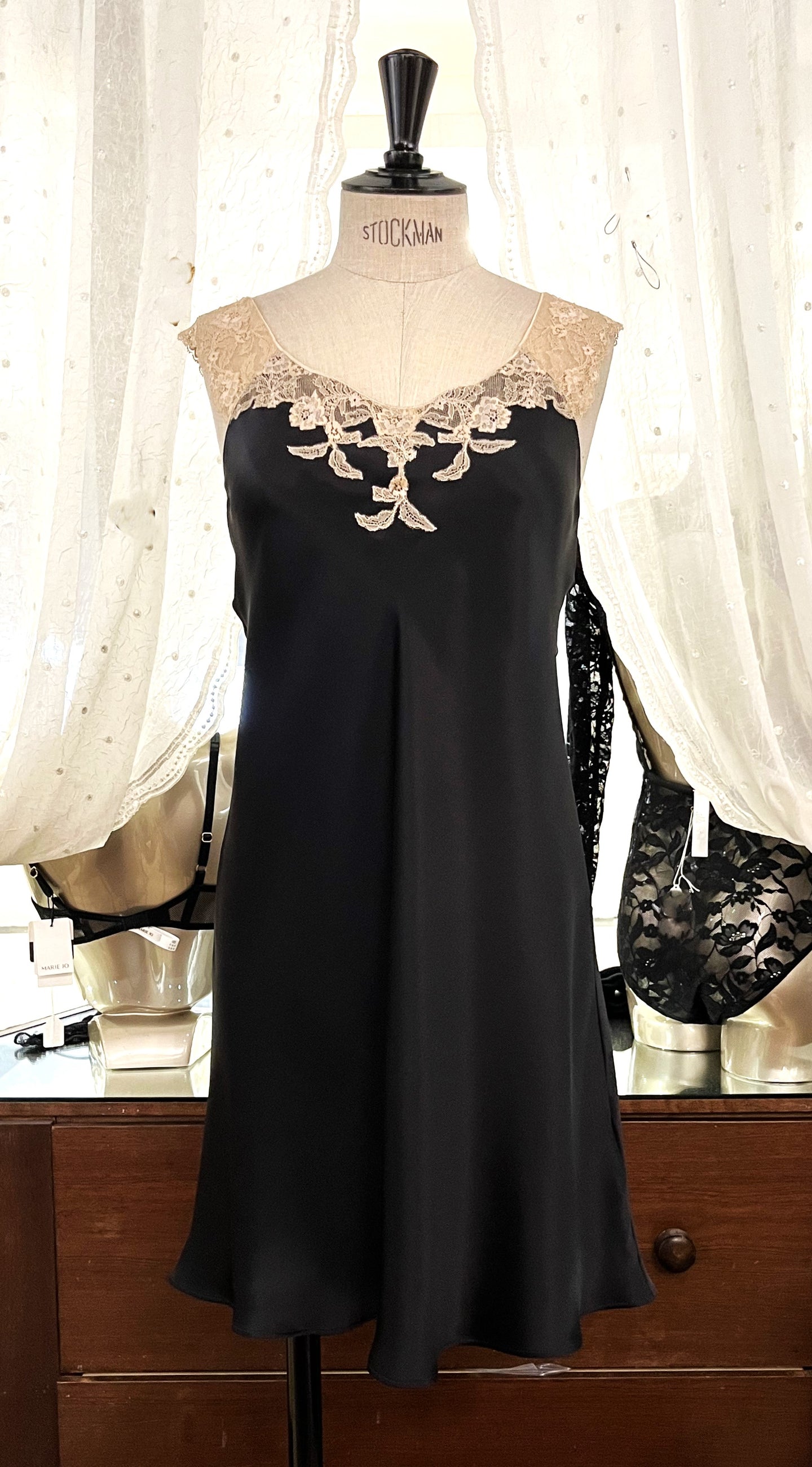 Black/Ecru. Classic, short night/slip. Made from 100% silk satin. The wide lace straps have a gentle elasticity for fit and comfort.  Appliqué lace detail continues to the round neck. Cut on the bias for movement and swing. This garment is perfect for sleepwear or loungewear. Generous sizing, if in doubt select the smaller size.   100% Silk Satin. Lace: 78% Nylon, 16% Elastane, 6% Polyester. Made in Italy. Machine washable.