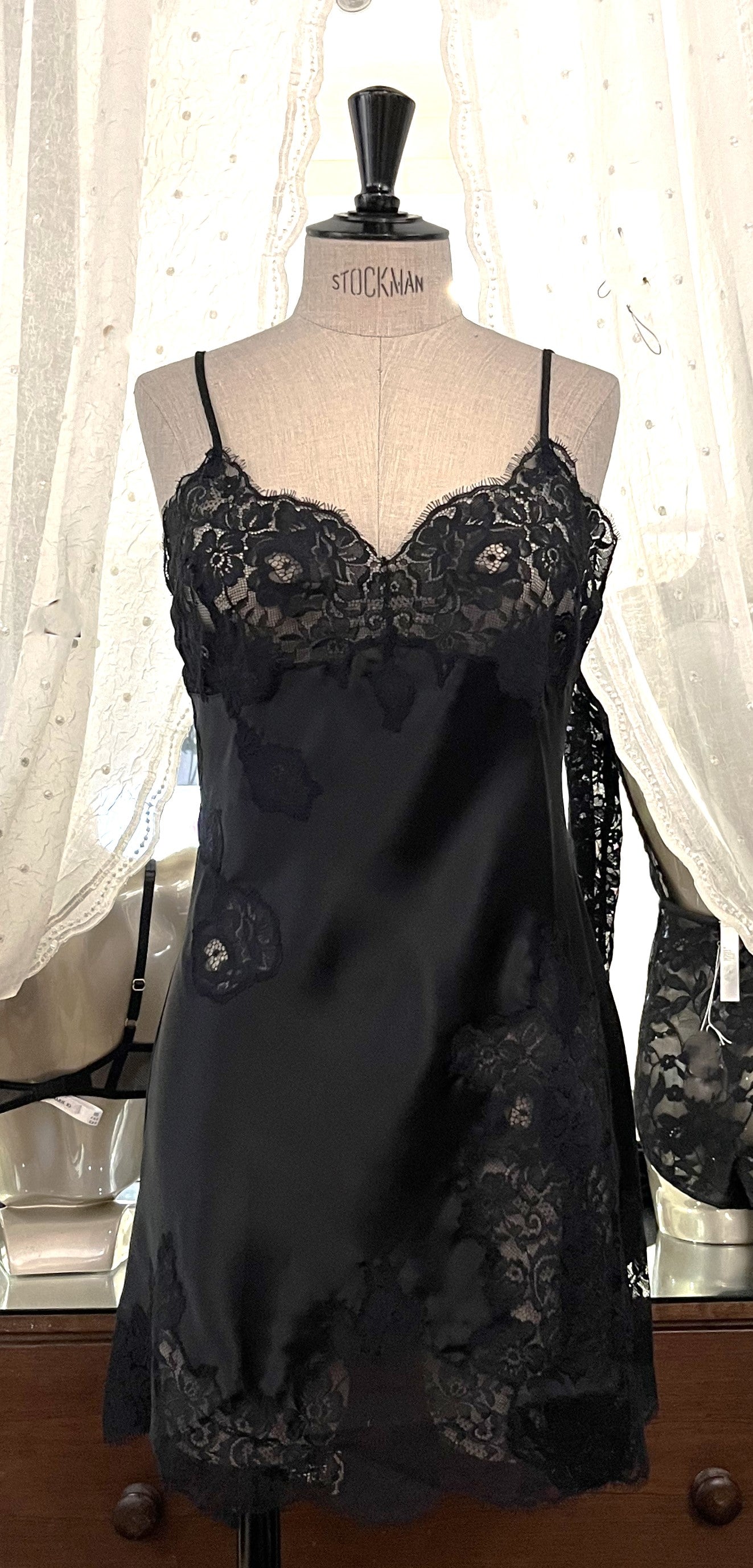 Made in Florence, Italy, this is a beautiful short pure silk satin night/slip. There is stunning deep appliqué lace on the bust and front of the garment. A side split leads to the hem, all with the same rich lace detail. There are French seams throughout for softness. The fine spaghetti straps are adjustable for the perfect fit. This nightslip is cut on the bias and panelled, giving lovely flare and movement. Perfect for bed or daywear. May be worn as underwear, nightwear or outerwear. Black/Black.