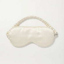 Load image into Gallery viewer, An ivory Pure silk satin sleep mask with a matching ruffled elastic strap, displayed flat against a clean white background. A small black brand tag on the right edge reads 'TYTTE'.
