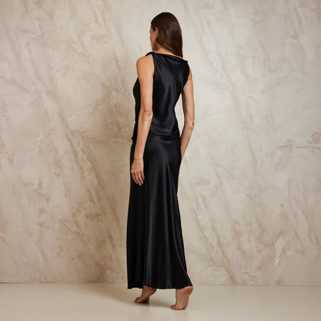 Woman wearing a black sleeveless Top and Slip Skirt against a beige marble background