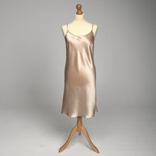 Load image into Gallery viewer, A silk satin slip dress in a champagne beige color, displayed on a mannequin against a neutral gray studio background.
