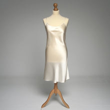 Load image into Gallery viewer, A silk satin slip dress in ivory color, displayed on a mannequin against a neutral gray studio background.
